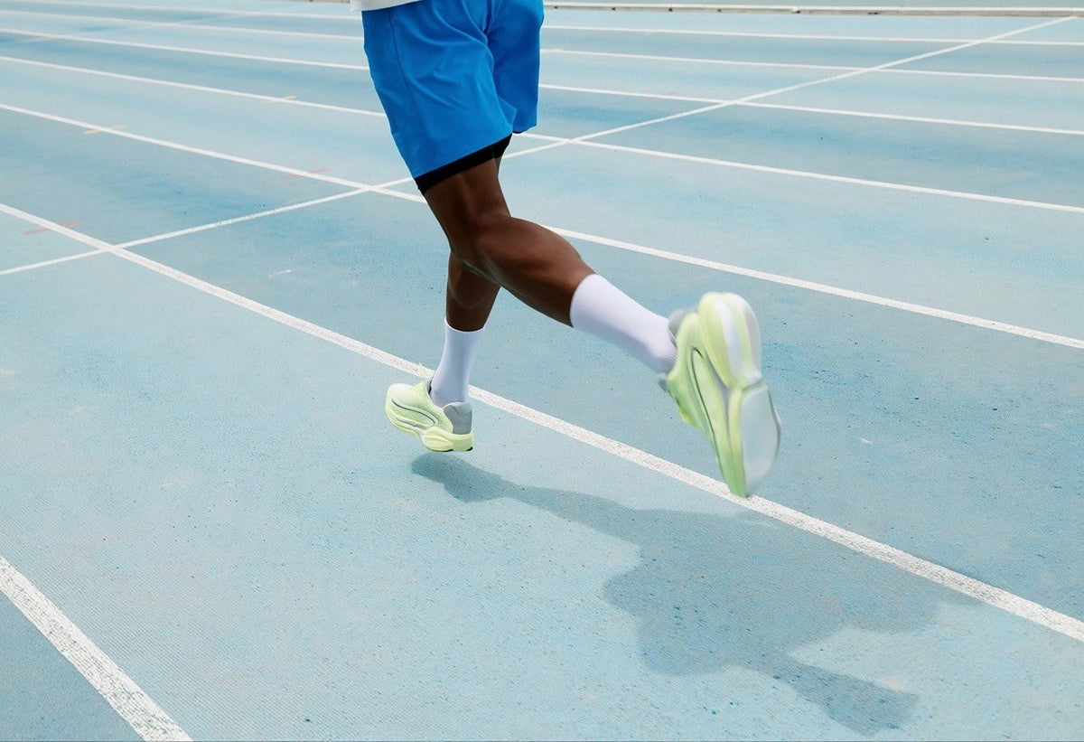 Runner in bright running shoes on a blue track
